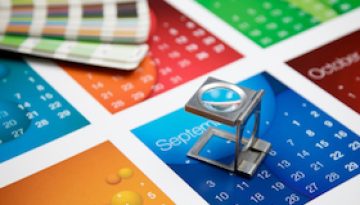 A printers eye glass sitting on a colourful calendar